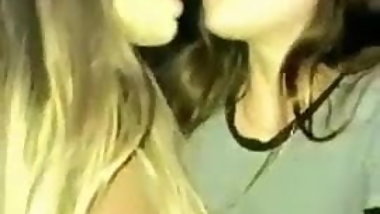 Girl kissing friend in a club embarrassed by hard nipples